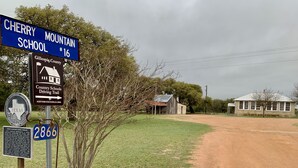 Eine Landstraße mit einem Schild für die Cherry Mountain School Nr. 16 und einem Schild für den Country Schools Driving Trail.