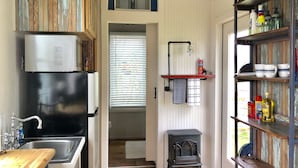 Eine kleine Küche mit Kühlschrank, Spüle und Holzschränken.