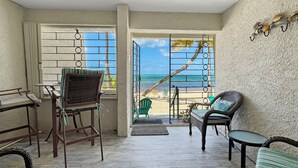 Una habitación con vista al mar, muebles de mimbre y una puerta que da al exterior.