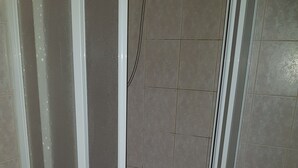Un bany amb plat de dutxa, vàter i parets revestides de rajoles.