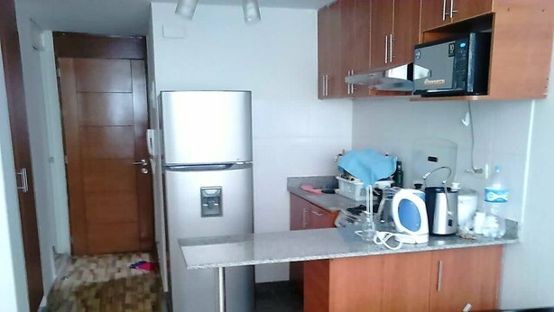 Una cucina compatta con frigorifero, forno a microonde e sgabelli da bar.