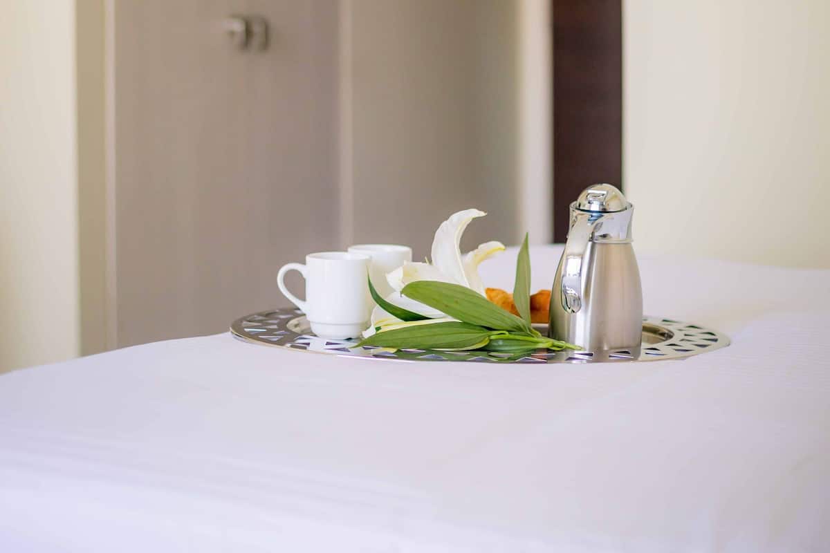 Une table de petit-déjeuner soigneusement dressée, avec un pichet, des tasses et un centre de table décoratif.