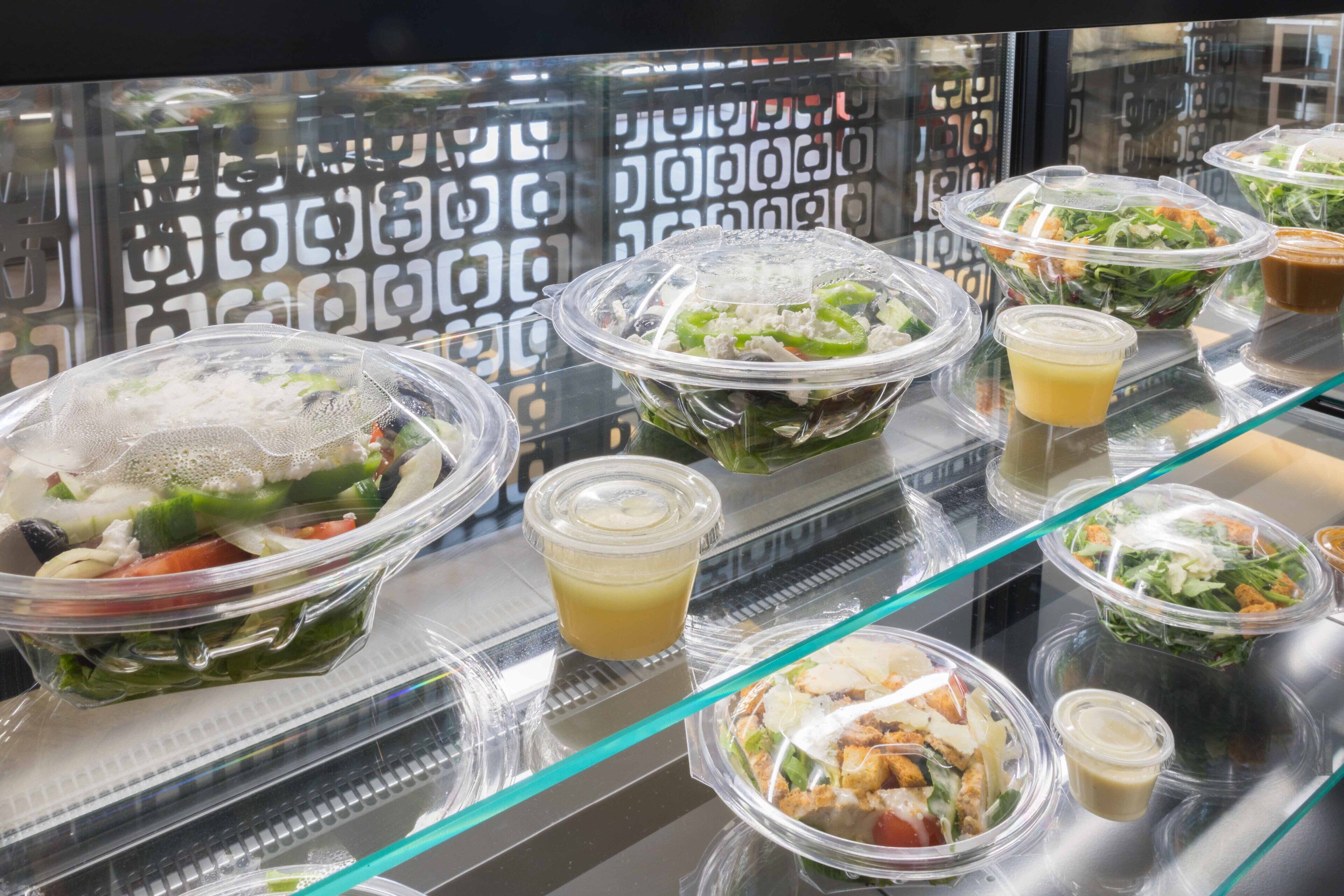 A display of various salad bowls and dressings in a restaurant setting.