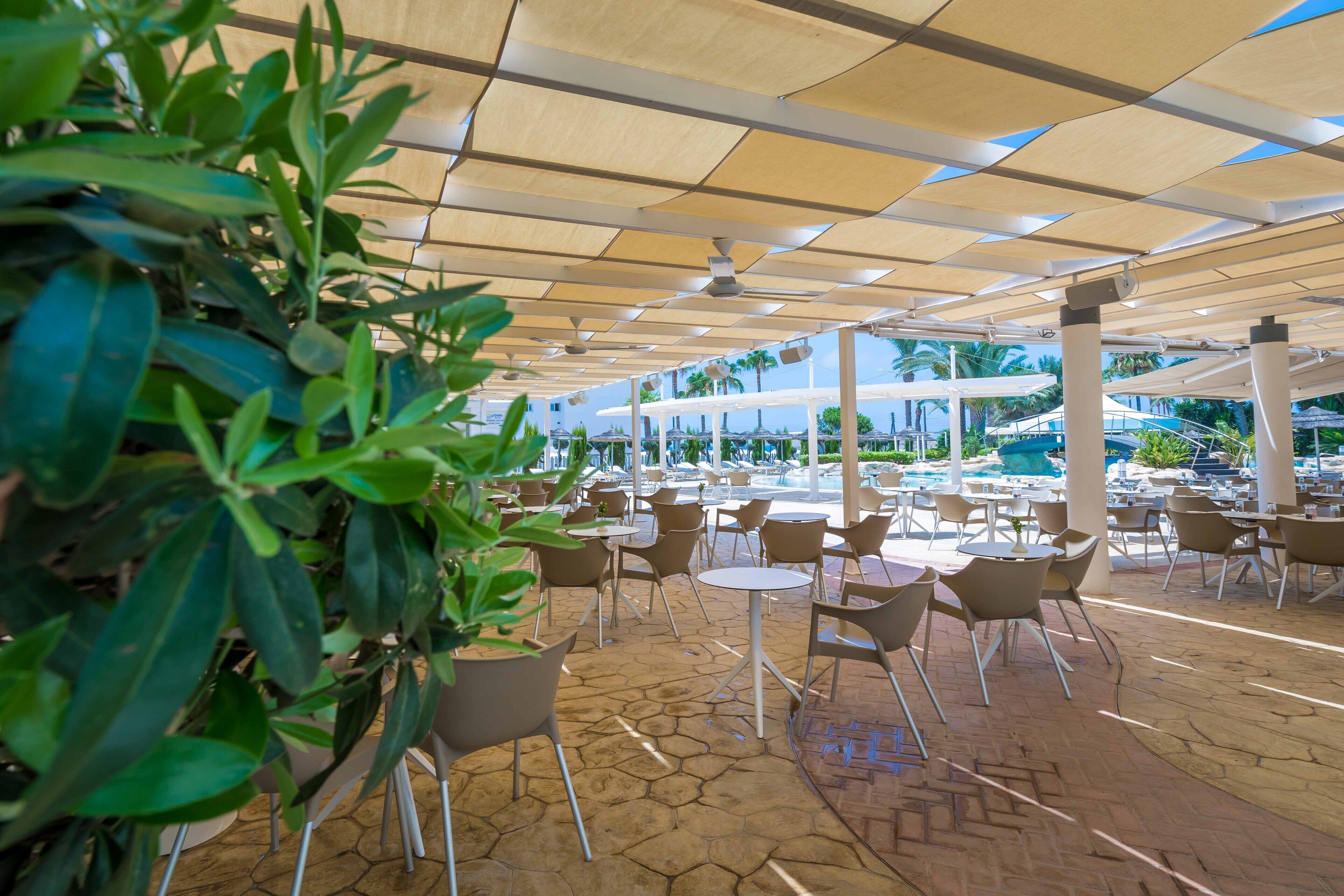 Un área de café al aire libre con suelo de patrón hexagonal, mesas y sillas redondas.