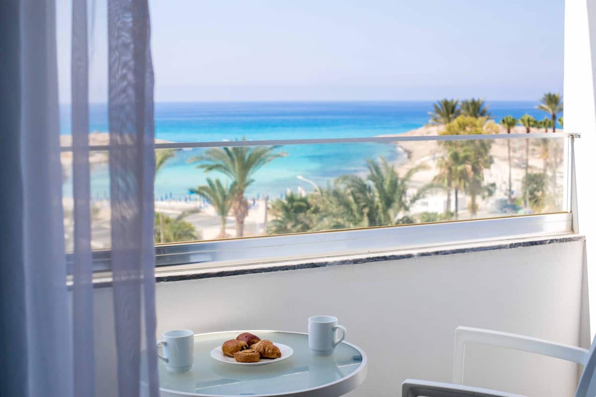 Un balcon avec une table, une assiette de croissants et une tasse.