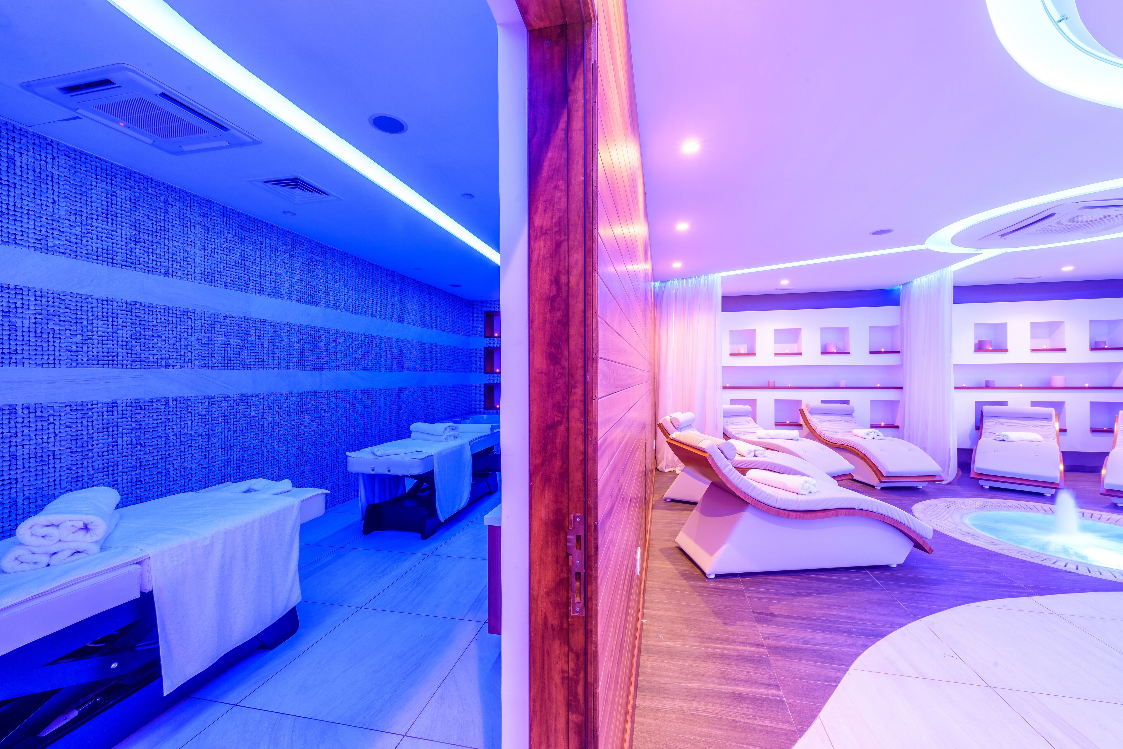 Une salle de spa équipée de tables de massage, d’un espace d’accueil et d’un élément décoratif aquatique.