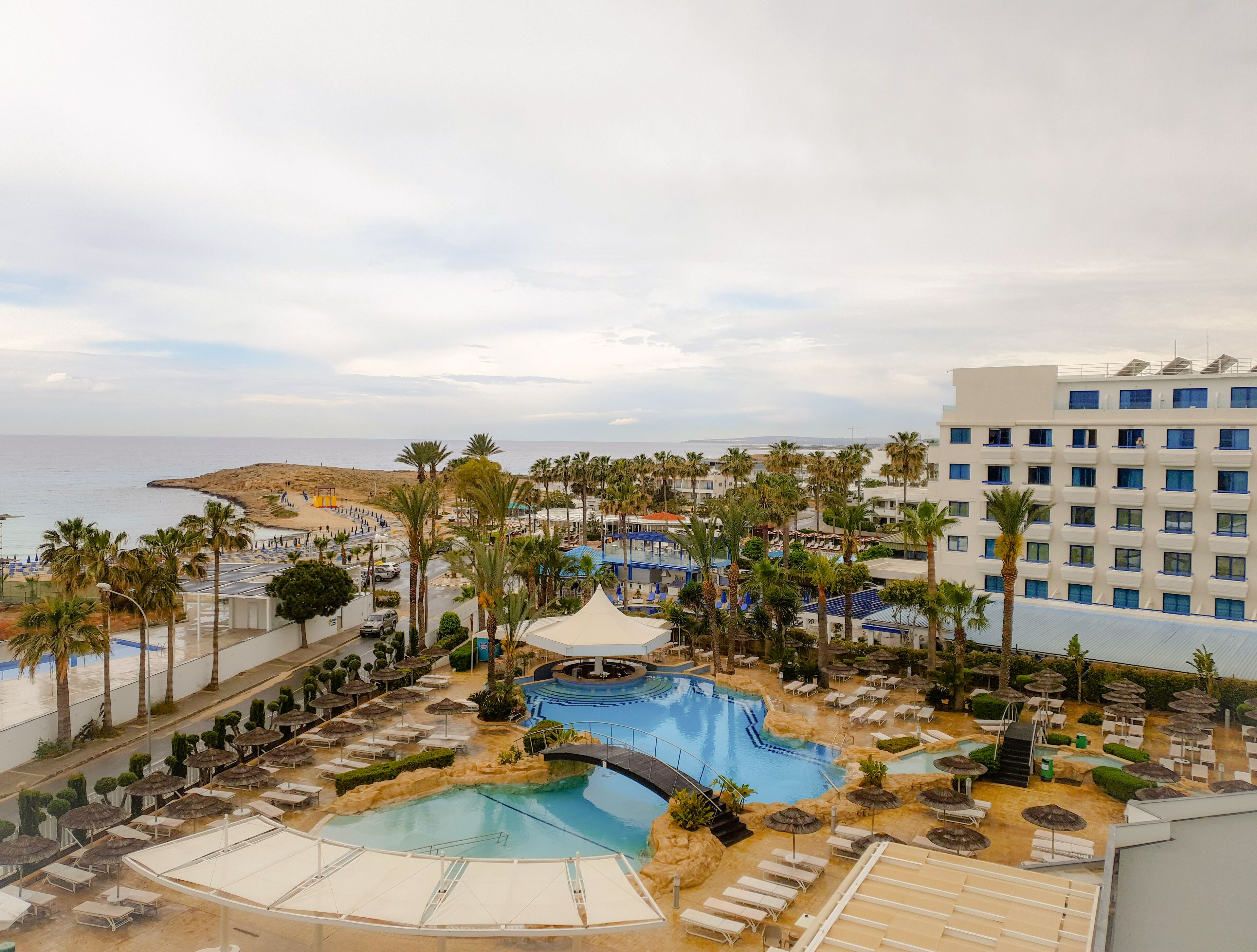 Un resort con piscina, palmeras y vistas al mar.