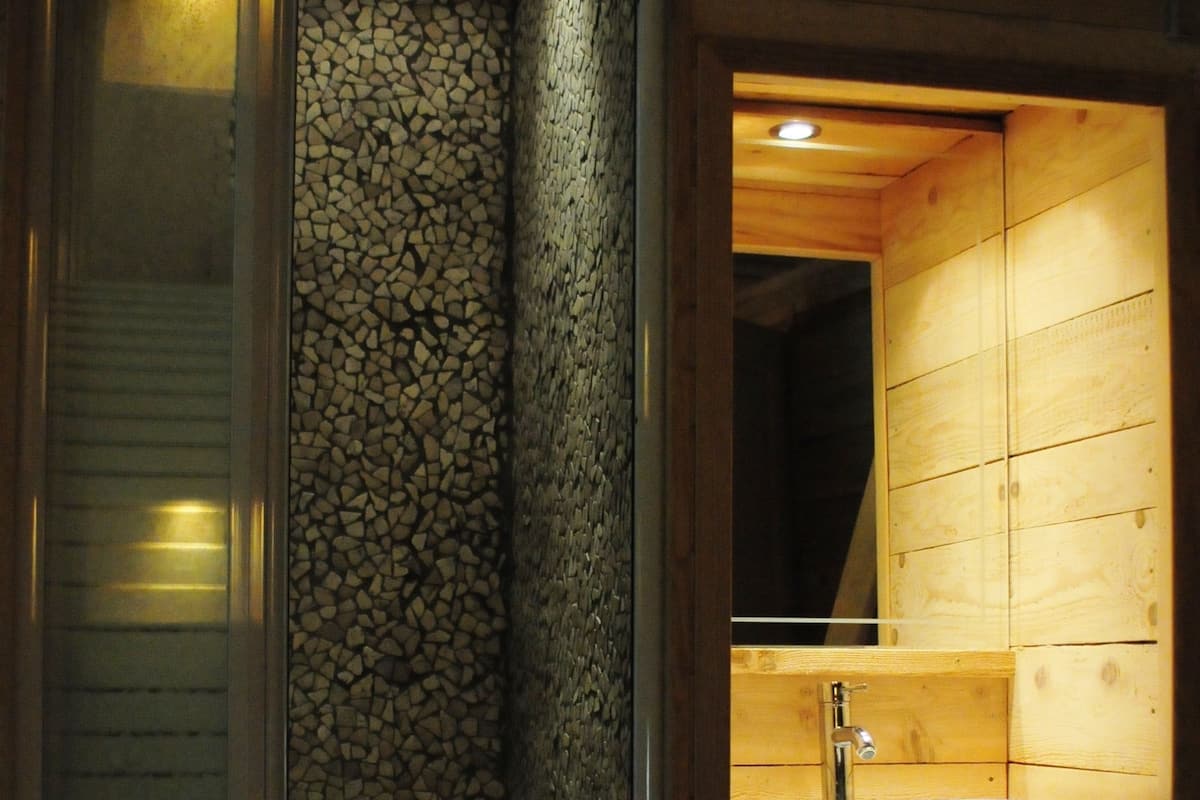 A wooden cabin with a stone wall, a wooden sink, and a mirror.