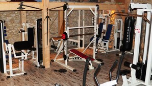 A gym with various exercise equipment including a bench press, weight machines, and a punching bag. - Réserve Naturelle de Boussière (Gigors-et-Lozeron)