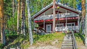 Une cabane dotée d’une terrasse en bois, entourée d’arbres.