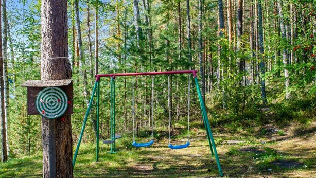 Une balançoire installée dans une zone boisée, avec une cible fixée sur un arbre.