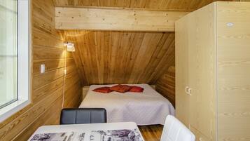 Ein kleines Zimmer in einer Holzhütte mit zwei Betten, einem Tisch und einem Schrank.