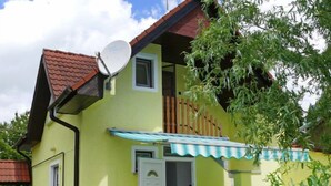 Uma casa de dois andares com antena parabólica, varanda e toldo azul.