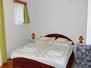 A bedroom with a bed, nightstands, a chair, and a window with curtains. - Michael by Interhome (Balatonfenyves)