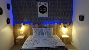 Une chambre à coucher moderne avec une tête de lit à motifs géométriques, deux lampes de chevet et un lit recouvert d’une couvre-lit à motifs géométriques.