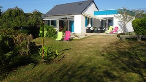 Une maison dotée d’un patio couvert, d’un espace salon extérieur et d’un jardin.