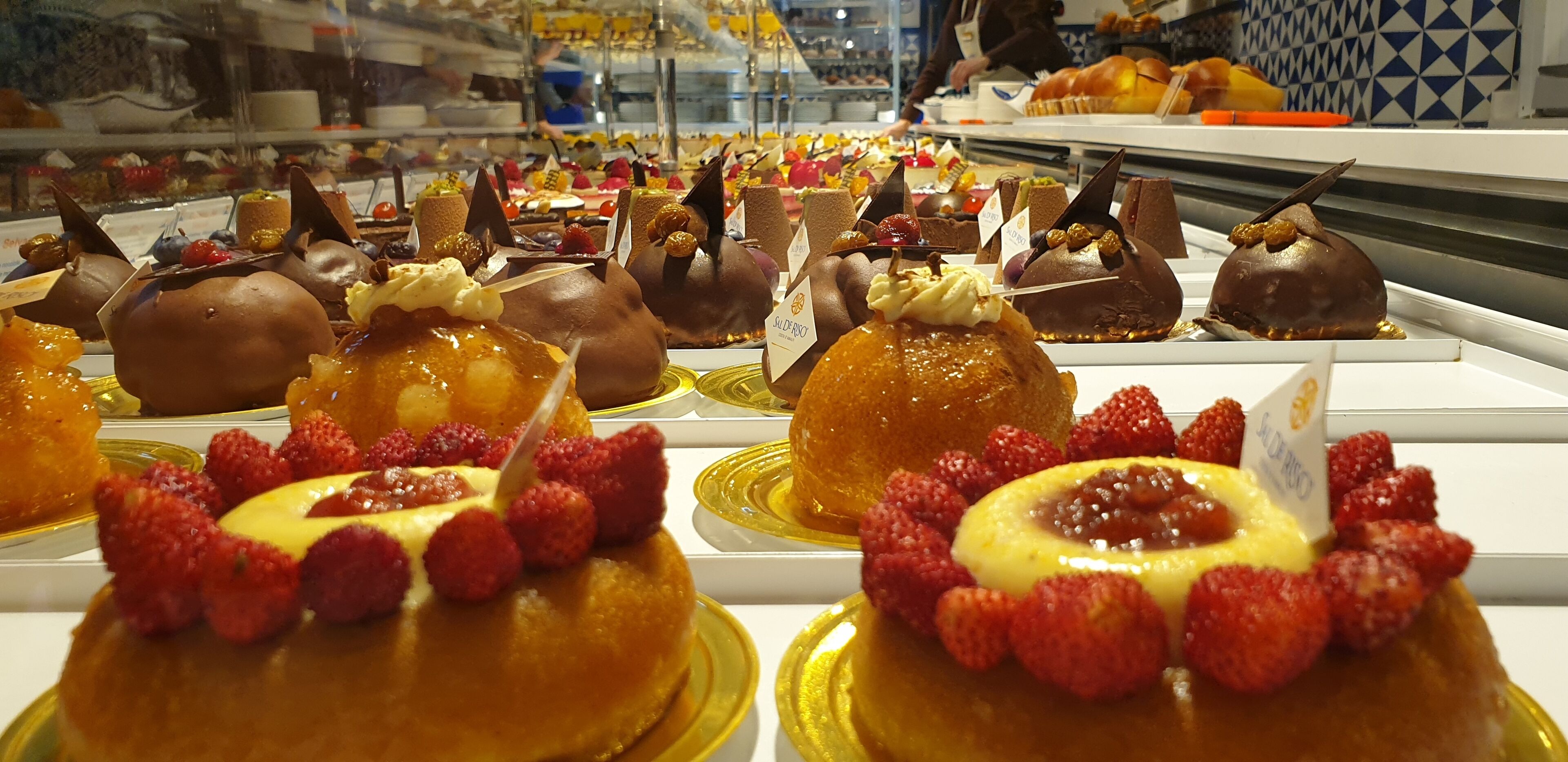 A display of various desserts in a bakery or cafe setting.
