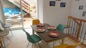 A dining area with a table set for four, surrounded by colorful chairs, a staircase, and a stone wall. - 18 kms from the Cité de Carcassonne, gîte in a maison de maître wifi spa patio (laure minervois)