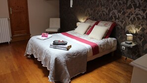 A bedroom with a bed, a chair, a nightstand, and a wooden door. - 18 kms from the Cité de Carcassonne, gîte in a maison de maître wifi spa patio (laure minervois)