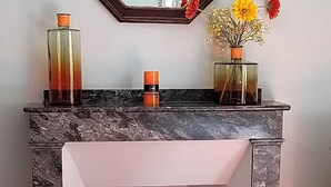 A corner desk with a marble top and a white drawer, positioned against a wall with a mirror and two vases with flowers. - 18 kms from the Cité de Carcassonne, gîte in a maison de maître wifi spa patio (laure minervois)