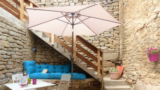 A cozy outdoor seating area with a blue sofa, a table with drinks, and a wooden staircase. - 18 kms from the Cité de Carcassonne, gîte in a maison de maître wifi spa patio (laure minervois)