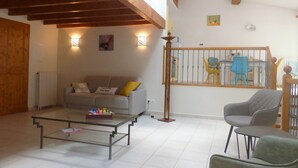 A living room with a sofa, a coffee table, and a chair. There is a staircase with a railing and a door leading to another room. - 18 kms from the Cité de Carcassonne, gîte in a maison de maître wifi spa patio (laure minervois)