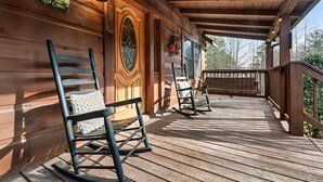 A wooden porch with rocking chairs and a welcome sign. - Porch w/ swing & hot tub, sounds of stream, fireplace, pet & family friendly! (Pigeon Forge)