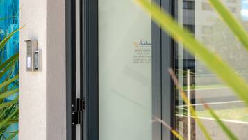 Puerta de cristal con un número de contacto y dirección para un hotel.