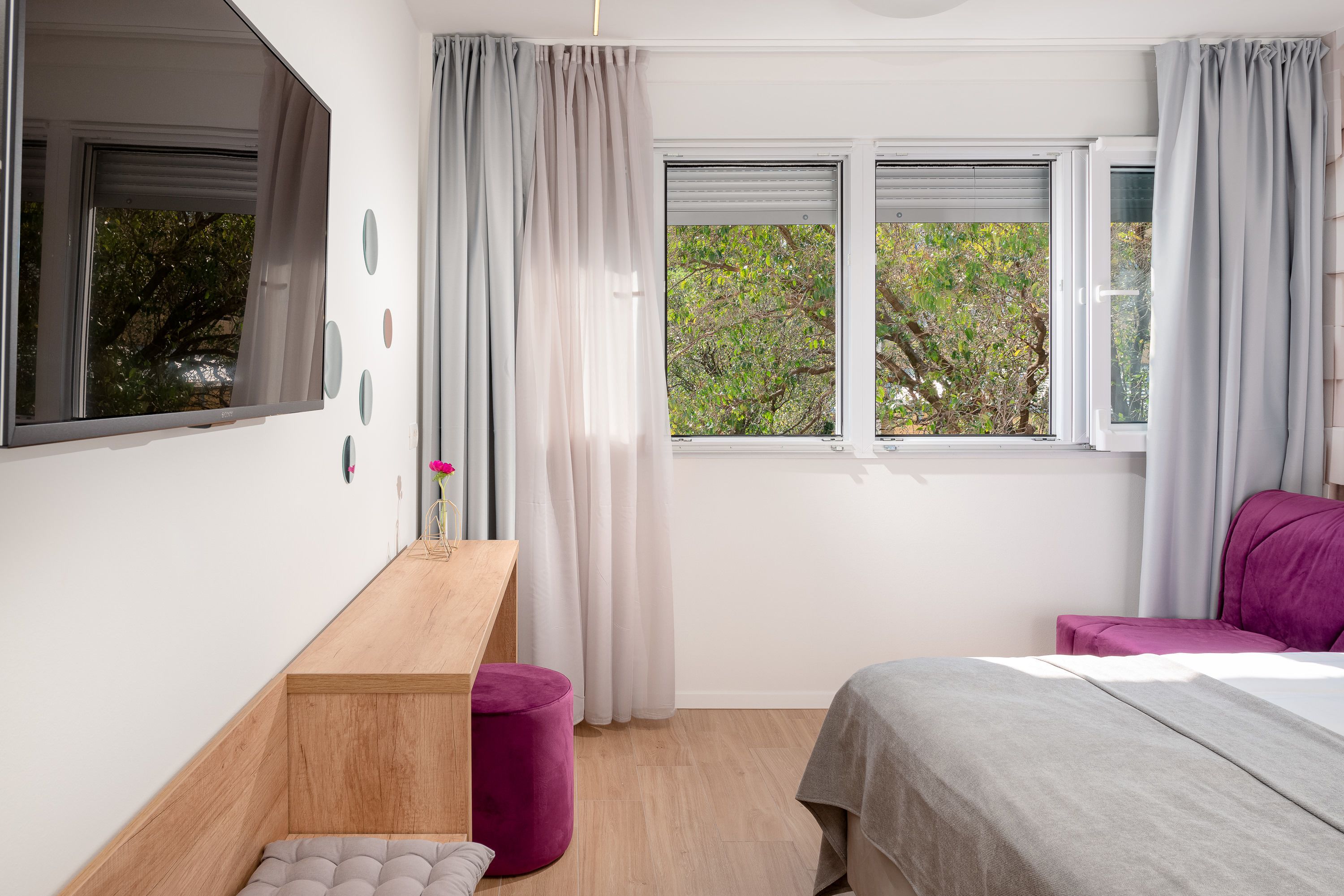 A bedroom with a bed, a desk, and a window with curtains.