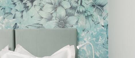 A neatly made bed with white linens, a grey throw blanket, and a white bedside lamp on a blue nightstand.