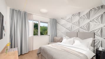 Een moderne slaapkamer met een groot bed, een nachtkastje, een raam met gordijnen en een geometrisch wandontwerp.
