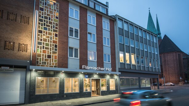 Ein Gebäude mit einer Schrifttafel mit der Aufschrift "Flämischer Hof" und einer Ziegel-Fassade.