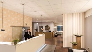 Eine Hotelhalle mit einer Rezeption, einer Sitzecke mit einer Couch und einem kleinen Tisch sowie einer Küche im Hintergrund.