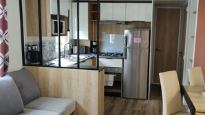 Une cuisine compacte dotée d’appareils électroménagers modernes, un coin repas avec une table et des chaises, et un canapé.