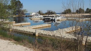 Un port de plaisance où sont amarrés des bateaux, entouré d’arbres et sous un ciel dégagé.