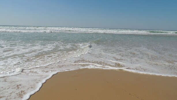 Une plage où les vagues viennent doucement lécher le rivage.