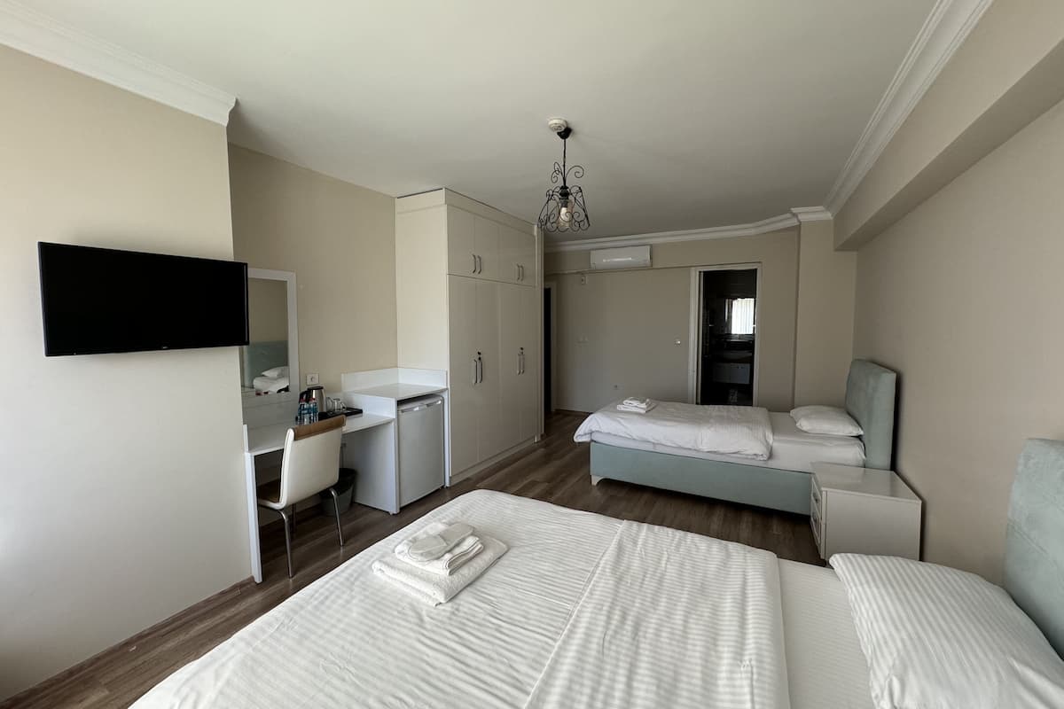 A hotel room with two beds, a desk, a chair, a wardrobe, and a television.