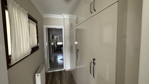 A narrow hallway with a radiator, white walls, and a door leading to a bathroom. - Doga Villa Guesthouse (Istanbul)