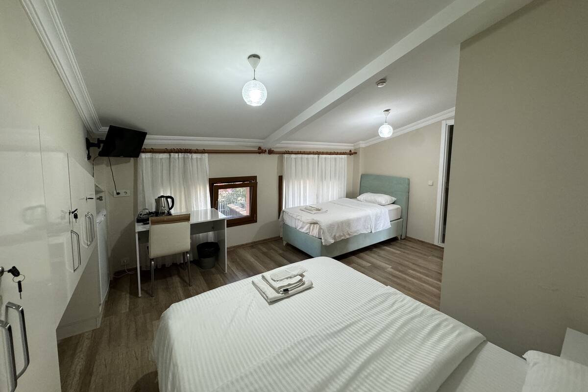 A hotel room with a bed, a desk, a chair, a television, and a window with curtains.