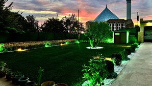 A well-maintained garden with a variety of potted plants, a lawn, and a building with a prominent tower. - Doga Villa Guesthouse (Istanbul)