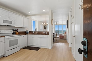 A kitchen with white cabinets, a microwave, stove, and a dining area with a view.