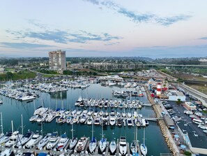 A marina with numerous boats docked, a bridge in the background, and a coastal cityscape. - Beachfront-Full Panoramic Ocean Views. D24 North Coast Village (Oceanside)