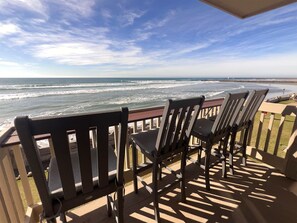 A balcony with wooden chairs overlooking a beach with waves and a clear sky. - Beachfront-Full Panoramic Ocean Views. D24 North Coast Village (Oceanside)