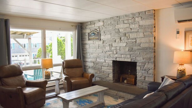 A cozy living room with a stone fireplace, leather chairs, a sofa, and a coffee table. - Seven bedroom directly across street from shared/private beach (Dennis Port)