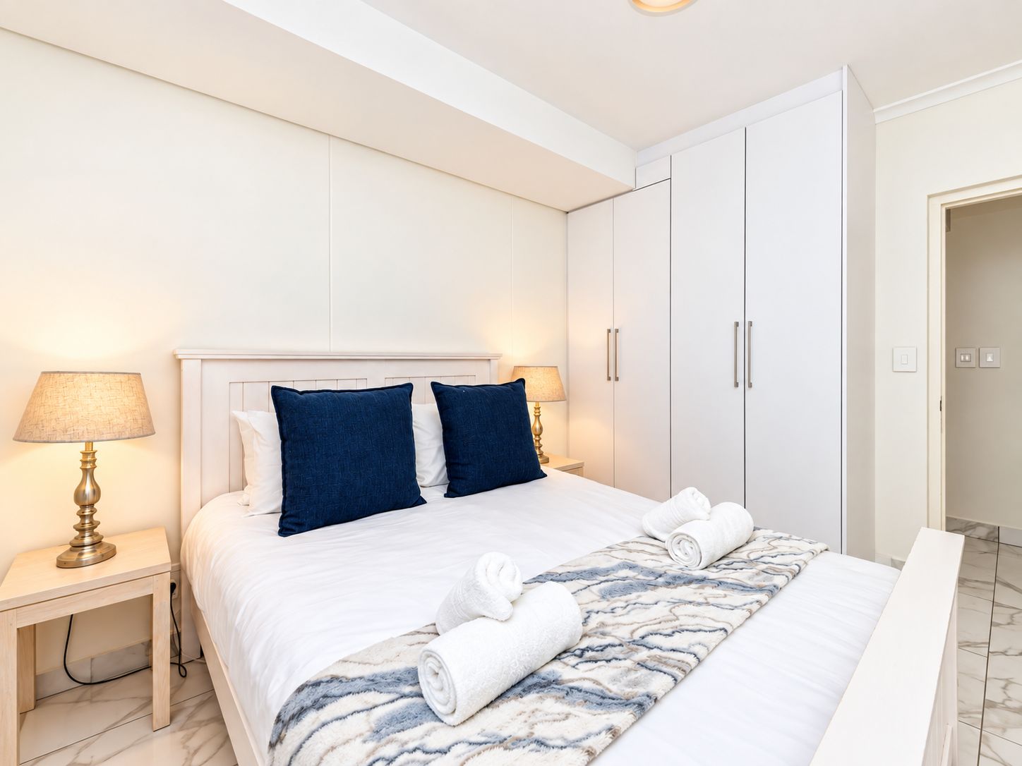 Habitación de hotel con cama, dos lámparas de noche, un armario y la puerta del baño.