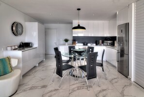 Una cucina moderna con mobili bianchi, un tavolo da pranzo in vetro e sedie nere.