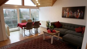 Un salon moderne comprenant un coin repas, un canapé, une table basse et un tableau accroché au mur.
