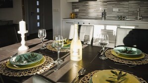 A dining table set with green plates, silverware, and a bottle of wine, with a candle and glassware on the table.