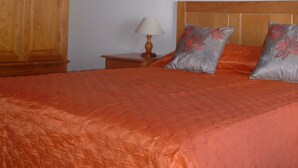 A bedroom with a wooden headboard, a nightstand with a lamp, and a bed with orange bedding. - Casa los Viñedos (A) with views of the sea, the mountains and the volcanoes. (Fuencaliente de la Palma)