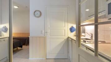 Une chambre d’hôtel avec un lit, une porte blanche, une horloge et une kitchenette.